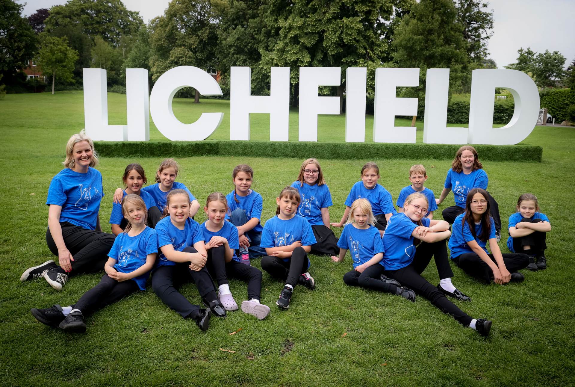 Young Voices choir sitting in front of Lichfield sign
